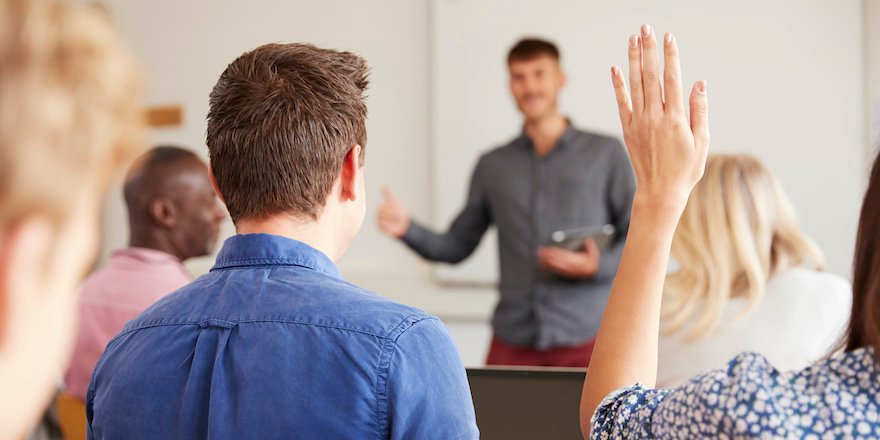 Rear View Of Mature College Student Asking Question In Class